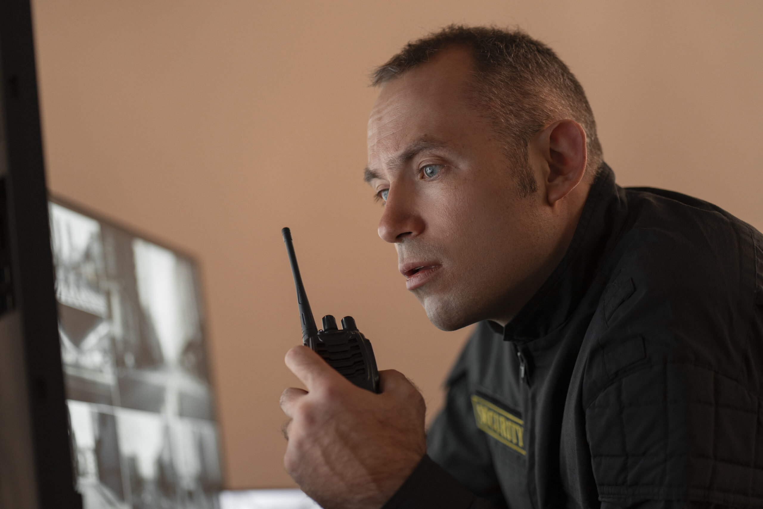 portrait male security guard with radio station camera screens 1 scaled